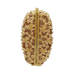 Macro detail of golden evening clutch bag featuring rhinestones and metal floral patterns