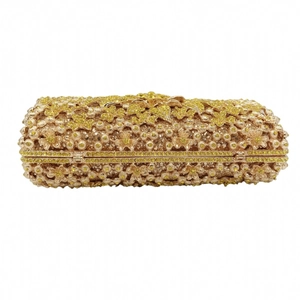 Close-up of golden evening clutch bag with intricate 3D floral rhinestone embroidery
