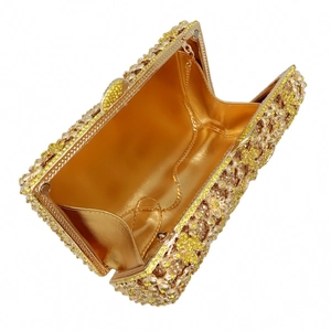 Macro detail of golden rhinestone evening clutch with floral pattern and silk lining