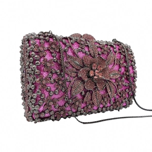 Detail of fuchsia glitter clutch featuring dark metal hollow floral patterns and smoky crystals