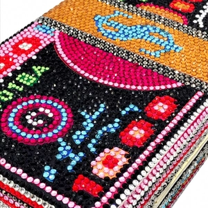 Macro view of crystal rhinestones on currency pattern clutch bag showing dollar details