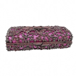 Close-up of purple glitter clutch bag with intricate gunmetal floral metal hollow pattern