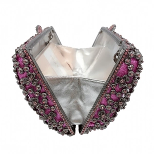 Detail of pink heart-shaped clutch with silver floral metal frame and shimmering sequins