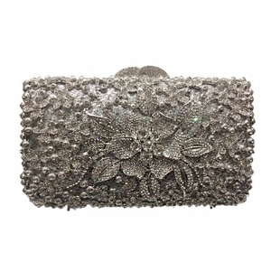 Detail of silver evening clutch featuring a large crystal floral motif and metal frame