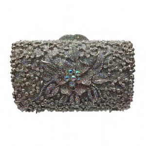 Macro detail of a silver evening clutch featuring intricate diamond flower patterns