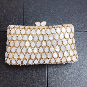 Top view of gold evening clutch with teardrop pearls and crystals on black background