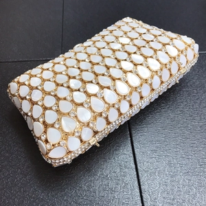 Detail of tear-drop shell embellishments and crystal studs on a gold frame clutch bag