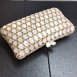 Detailed close-up of luxury clutch with teardrop shell inlays and crystal butterfly clasp