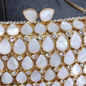 Macro detail of luxury teardrop pearl and crystal evening clutch with gold metal frame