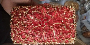 Close-up of red rhinestone flower evening clutch with hollow gold metal frame detailing