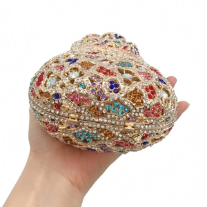 Close-up of heart-shaped evening clutch bag with colorful rhinestones and gold metal craft