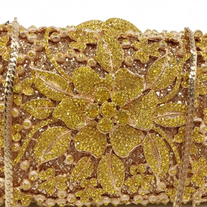 Close-up of golden floral metal evening bag featuring intricate yellow rhinestones and chain