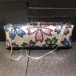 Close-up of elegant floral crystal clutch with colorful rhinestones and silver chain strap