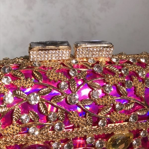 Luxurious fuchsia evening clutch with intricate gold leaf pattern and sparkling crystals