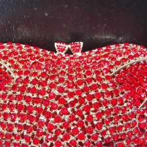Luxe red rhinestone evening clutch bag with gold trim and bow-shaped diamond clasp lock