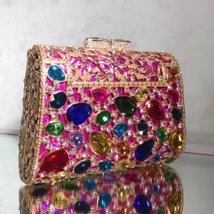 Detail of colorful water-drop gemstones and gold filigree on luxury magenta evening bag