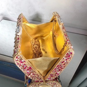 Open evening clutch showing gold lining, rhinestone exterior, and removable chain strap