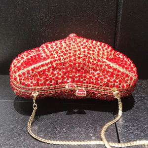 Macro shot of heart-shaped evening clutch with red rhinestones and gold chain