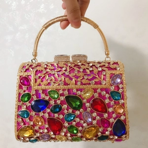 Close-up of luxury evening bag with colorful gemstones and golden metal cut-out patterns