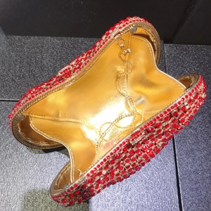 Detailed interior of red heart evening clutch bag with gold lining and metal chain strap
