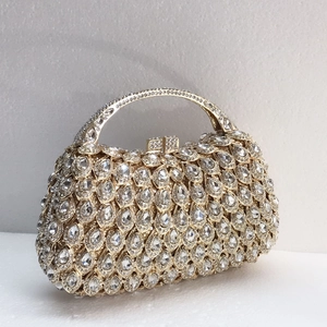 Detail view of champagne gold evening clutch with sparkling crystals and metal handle