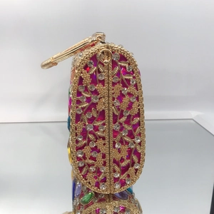 Detail of evening clutch featuring golden floral filigree and vibrant fuchsia lining