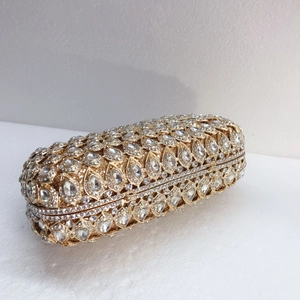 Close-up of golden hollow metal clutch with rhinestones and teardrop gemstone mandala