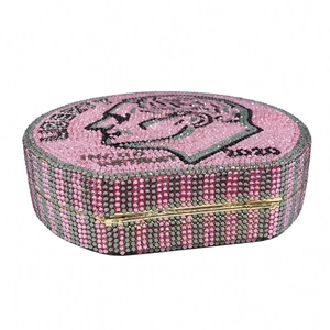 Detail of a round coin evening clutch with pink rhinestones and a 2020 Liberty portrait