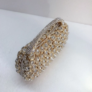 Detail of luxury evening clutch bag featuring intricate crystal patterns on gold alloy frame