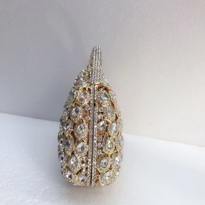 Detailed side view of luxury gold hollow metal clutch with sparkling rhinestone inlay