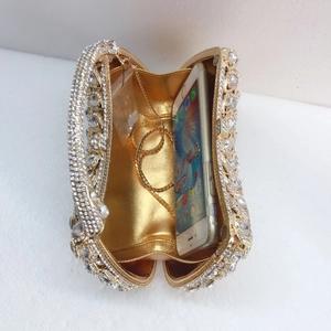 Golden evening clutch bag with sparkling rhinestones and chain showing interior capacity