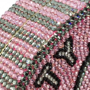 Macro shot of pink and grey rhinestones with black letter patterns on evening clutch bag