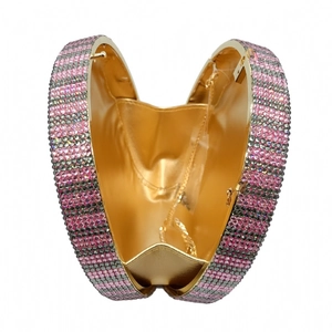 Detail of heart-shaped evening clutch featuring striped pink rhinestones and gold interior