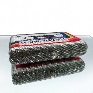 Macro view of crystal-encrusted cassette tape clutch bag with rainbow stripes and metal clasp
