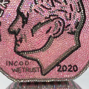 Close-up of sparkling pink rhinestone evening bag with intricate coin pattern engraving