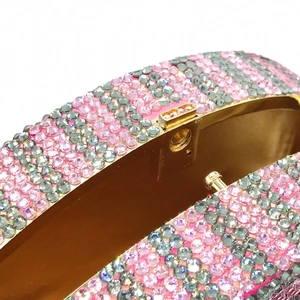 Macro shot of striped pink rhinestone clutch with a sturdy gold metal clasp mechanism