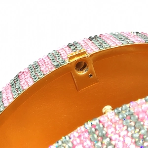 Macro shot of gold hinges and pink rhinestone stripes on a dollar coin evening clutch bag
