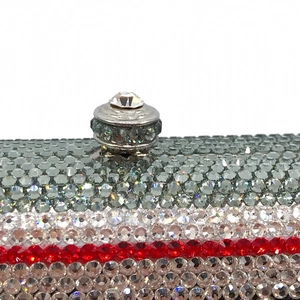 Macro detail of multicolored crystals and metal round clasp on a cassette evening bag