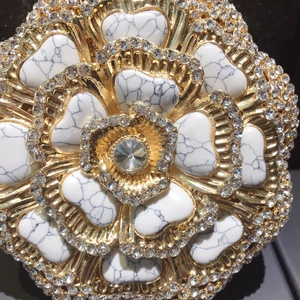 Macro detail of luxury floral evening bag clasp with marble inlay and crystals