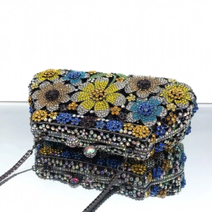 Detailed macro view of colorful rhinestone flower pattern and crystal clasp on evening bag