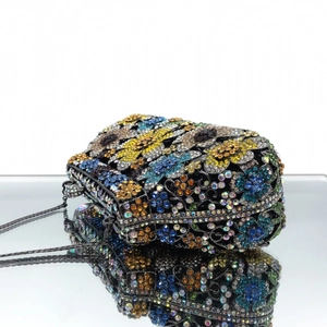 Detail of colorful sunflower rhinestone evening clutch bag with dark metal frame and chain
