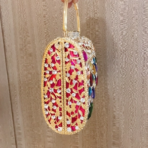 Detail of gold oval evening clutch with colorful rhinestones and hollow leaf metalwork