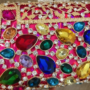 Macro detail of luxury evening clutch featuring colorful gemstones and gold leaf engraving