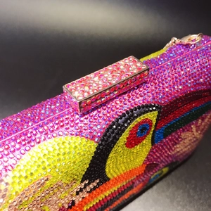 Detail of pink crystal evening bag with colorful bird motif and diamond encrusted clasp