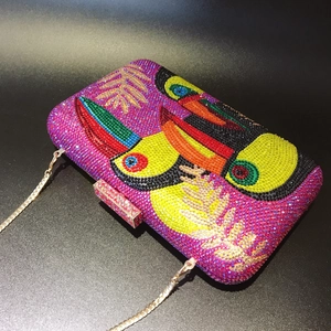 Detail of evening clutch with colorful rhinestone tropical bird and gold chain strap