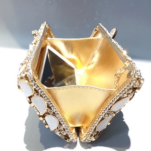 Luxury shell-shaped evening clutch bag with diamonds and gold chain shown open with phone