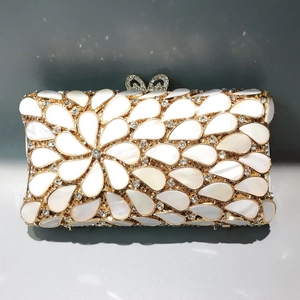 Detail of evening clutch with gold metal frame, shell inlay and rhinestone bow clasp