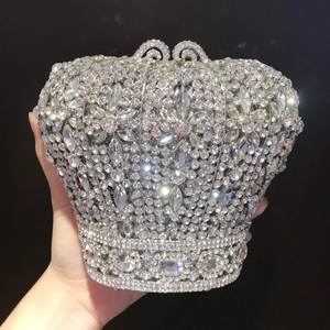 Pochette de soirée en forme de couronne avec strass brillants tenue par une main