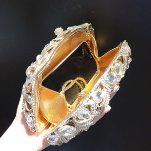 Innenansicht der goldenen Kristall-Clutch mit Smartphone zeigt den Stauraum der Tasche