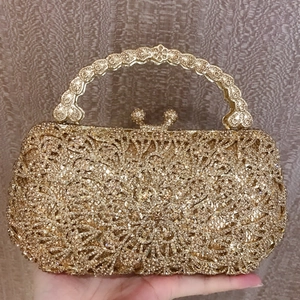Close-up of gold evening clutch bag with sparkling rhinestones and floral cutouts